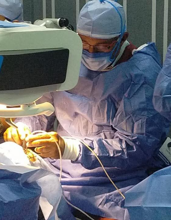 The consultant performing eye surgery in theatre